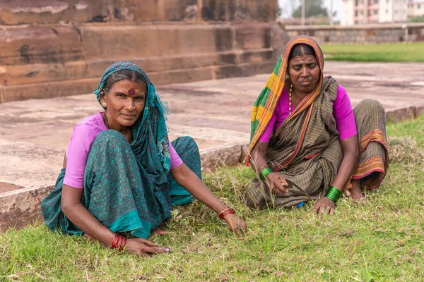 アイホール カルナータカ インド 2013年11月7日 フッチマーリ グディまたは神殿 草を短くするために緑の芝生の上に座ってカラフルな服の2人の女性庭師を見上げます 褐色の石の背景 — ストック写真
