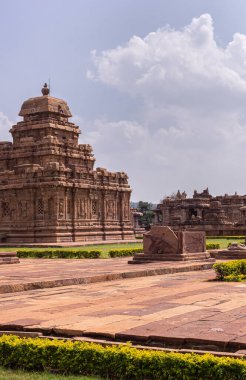 Bagalakote, Karnataka, Hindistan - 7 Kasım 2013: Pattadakal Tapınağı Kompleksi. Kahverengi taş Sangameshwara Tapınağı açık mavi bulutların altındaki diğer binalar arasında yeşil parka kurulmuştur..
