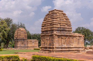 Bagalakote, Karnataka, Hindistan - 7 Kasım 2013: Pattadakal Tapınağı Kompleksi. Kahverengi taş Jambulingeshwara tapınağı ve mavi bulutların altında yan yana ve yeşil parkta geçiyor..