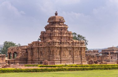 Bagalakote, Karnataka, Hindistan - 7 Kasım 2013: Pattadakal Tapınağı Kompleksi. Kahverengi taş Sangameshwara tapınak binası önünde mavi bulutların altında ve yeşil parka kurulmuş..