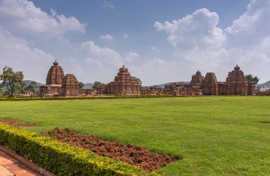 Bagalakote, Karnataka, Hindistan - 7 Kasım 2013: Pattadakal Tapınağı Kompleksi. Mavi bulutların altında kahverengi binaların ve yeşil çimlerin altında geniş manzara manzarası var..