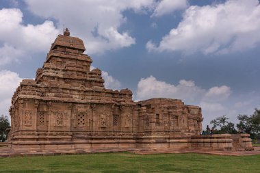 Bagalakote, Karnataka, Hindistan - 7 Kasım 2013: Pattadakal Tapınağı Kompleksi. Mavi bulutların altında, kahverengi taştan Virupaksha tapınağının yan tarafında. Yeşil çimenler ve ziyaretçiler renk katar.