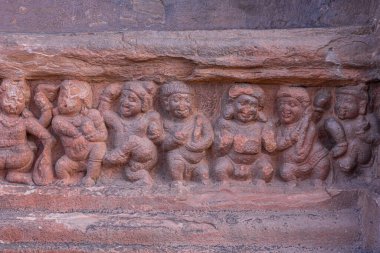 Badami, Karnataka, Hindistan - 7 Kasım 2013: Agasthya Gölü üzerindeki mağara tapınakları. Dans eden ve neşeli olan küçük insan figürlerinden oluşan sıra sıra taştan heykellerin yakın çekimi.