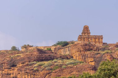 Badami, Karnataka, Hindistan - 7 Kasım 2013: Agasthya Gölü üzerindeki mağara tapınakları. Kahverengi taş, Yukarı Shivalaya Tapınağı. Mavi gökyüzünün altında, gölün karşı kıyısında, kızıl kayalık tepede..
