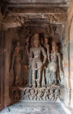 Badami, Karnataka, Hindistan - 7 Kasım 2013: Agasthya Gölü üzerindeki mağara tapınakları. Harihara, Shiva ve Vishnu 'nun eşleri Parvati ve Lakshmi ile birleşiminden oluşan kırmızı gri heykeller..
