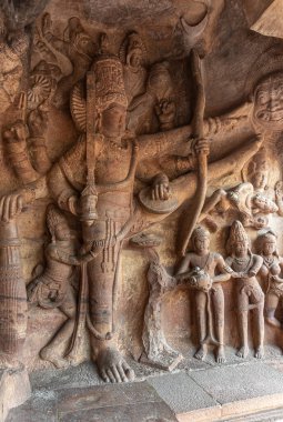 Badami, Karnataka, Hindistan - 7 Kasım 2013: Agasthya Gölü üzerindeki mağara tapınağı. Trivikrama olarak Vishnu heykeli ilk adımı atıyor. Kılıcı ve yılanı elinde tutuyor, üstünde yılanlar var..