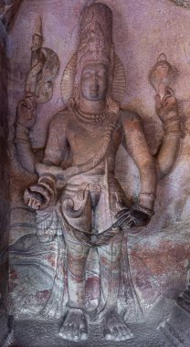 Badami, Karnataka, Hindistan - 7 Kasım 2013: Agasthya Gölü üzerindeki mağara tapınakları. Kahverengi-gri-yeşil tavalar tek başına Vishnu 'nun 3. Mağarada heykeli.