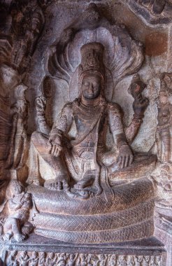 Badami, Karnataka, Hindistan - 7 Kasım 2013: Agasthya Gölü üzerindeki mağara tapınakları. Vishnu 'nun kahverengimsi taş heykeli 3 numaralı mağaradaki yılan Sesha' nın üzerinde oturuyordu..