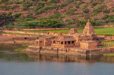 Badami, Karnataka, Hindistan - 7 Kasım 2013: Agasthya Gölü 'nün doğu kıyısındaki Bhootnath Tapınağı' nın kapatılması. Günbatımının altında kızıl kaya tepeleri. 