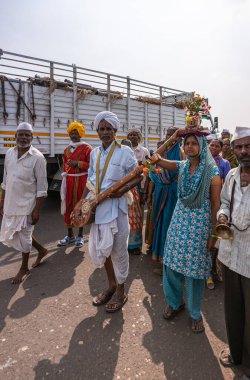 Jamunai, Karnataka, Hindistan - 8 Kasım 2013: Kamyon, Pandrapura 'daki Krishna Tapınağı' na yürüyen bir hacı grubunu geçer. Kadın kafasında Tulasi bitkisi taşıyor. Birinin elinde tambura müzik aleti var..