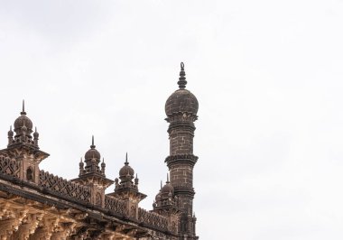 Vijayapura, Karnataka, Hindistan - 8 Kasım 2013: Açık mavi bulutlar altında İbrahim Rauza mozolesinin kahverengi taş köşeli minare ve çatı heykelleri. 