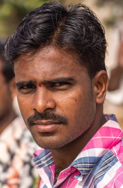 Ayodhya, Karnataka, Hindistan - 9 Kasım 2013: Pembe-beyaz-mavi gömlekli, siyah saçlı ve bıyıklı genç çiftçinin portresi.