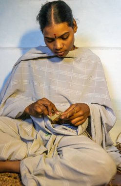 Anegundi, Karnataka, Hindistan - 9 Kasım 2013: Lepakshi El Sanatları kar amacı gütmüyor. Genç bayan sanatçı muz ipliği maskesi yapmak için yeni bir projeye başladı. Gri şal ve pantolon.