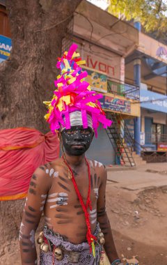 Hospital, Karnataka, Hindistan - 10 Kasım 2013: Umumi utanç, Tövbe ve ceza için siyah yüz olarak resmedilen genç çocuk. Renkli şapka. Kemer takılı. Yerel dükkan arka plan olarak ön plana çıkıyor