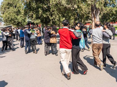 Pekin, Çin - 29 Nisan 2010: Cennet Tapınağı. Birçok çift yeşil ağaçlar ve çimlerle parktaki beton zeminde birlikte dans ediyor. Giysiler canlı renkler ekler.