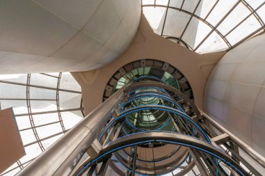 Şangay, Çin - 4 Mayıs 2010: Zemin kattan asansör boşluğuna oradan da Oriental Pearl TV kulesinin tepesine. Bej sütunlar, gri gökyüzü camdan pencereler ve mavi ışıklı jantlar.