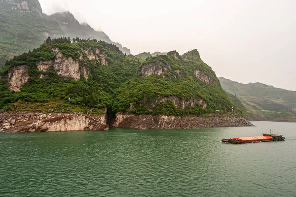 2010年5月6日 Zigui地域 緑の森の丘や海岸線に大きな茶色の崖と山の前に緑の水にオレンジのカバーバージ帆 — ストック写真