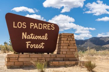 Los Padres Ulusal Ormanı, CA, ABD - 21 Mayıs 2021: Mavi bulutların altındaki parkın girişindeki kahverengi tabelada Bej 'in Kapanışı. Kuru ve yeşil bitki örtüsü.