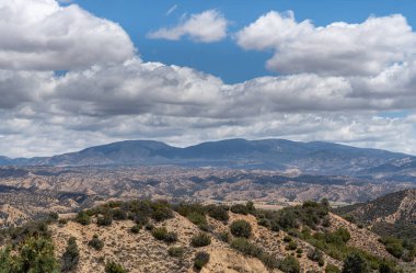 Los Padres Ulusal Ormanı, CA, ABD - 21 Mayıs 2021: Doğu yakası parkı üzerinde ağır mavi bulutlu manzara. Bej rengi, kahverengi, çıplak taşlar ve her yere serpiştirilmiş yeşil çalılar..