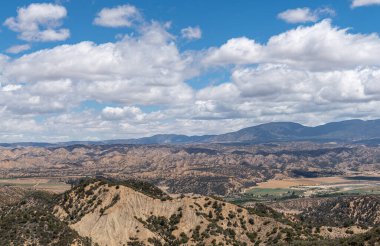 Los Padres Ulusal Ormanı, CA, ABD - 21 Mayıs 2021: Doğu yakasındaki kurak sıradağlar vadide tarımla birlikte ağır mavi bulutlar altında. Çalı bitkisi.