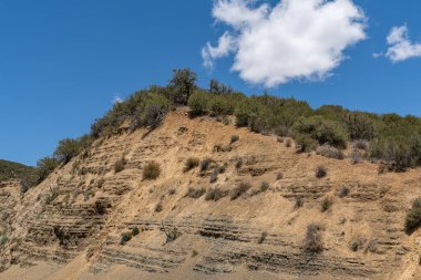 Los Padres Ulusal Ormanı, CA, ABD - 21 Mayıs 2021: 33 yolu boyunca mavi bulutların altında yeşil çalılık ile kahverengi kaya uçurumunun kapatılması.