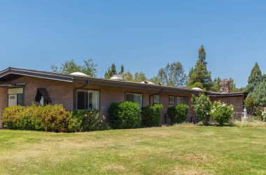 Santa Inez, CA, USA - 26 Mayıs 2021: San Lorenzo Papaz Okulu. Mavi gökyüzünün altındaki çimenlikte ve bahçede inşa edilmiş düşük katlı ofis binası. Birkaç beyaz dini durum mevcut..