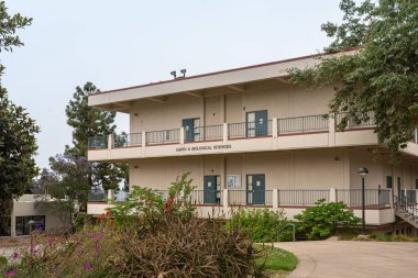 Santa Barbara, CA, USA - 2 Haziran 2021: Şehir kolej tesisleri. Bej rengi Eart ve Biyolojik Bilimler gri gökyüzünün altında yeşil manzaralı bir bina. çiçekler renk ekler.
