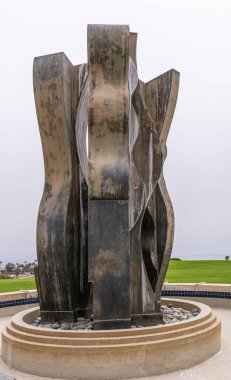 Santa Barbara, CA, USA - 2 Haziran 2021: Şehir kolej tesisleri. Metal heykel ve çeşme, adı Mentors. Batı kampüsünün ortasında, gümüş gökyüzüne karşı. Okyanus ve çimen.