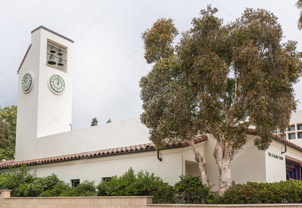 Santa Barbara, CA, USA - June 2, 2021: City College facilities. The Fe Bland Forum clock tower on beige modern building under silver sky and green foliage up front.