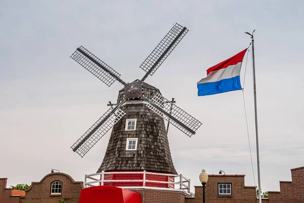 オランダ 2008年6月8日 ネリス オランダ村 黒灰色の風車とオランダの旗は 明るい青空に向かって旗を翻します レンガ建築の赤い部分 — ストック写真