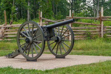 Gettysburg, PA, USA - 14 Haziran 2008: Savaş alanı anıtları. Kahverengi çimento üzerinde parlayan varilli, ahşap çitli ve yeşil yapraklı top mermilerinin yakınına..