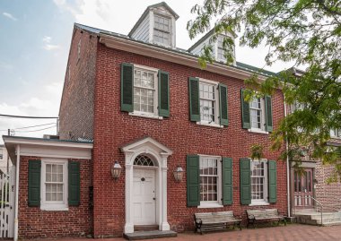 Gettysburg, PA, USA - 14 Haziran 2008: Beyaz çerçeveli pencereleri ve kapıları ve yeşil dış panjurları olan iyi bakımlı bir yüzyıllık kırmızı tuğla ev. Mavi bulutlu ve yeşil yapraklı. 