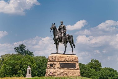 Gettysburg, PA, USA - 14 Haziran 2008: Savaş alanı anıtları. Tümgeneral George Meade binicilik bronz heykeli mavi bulutların altında bej kayalık kaidede. Arkadaki yeşil yapraklar.,
