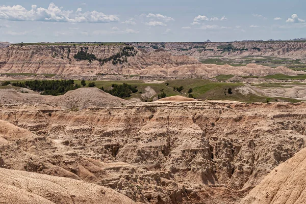 Badlands National Park Usa 2008年6月1日 ベージュ色の茶色の地質学的堆積物の峡谷の壁の閉鎖と それらの多くは明るい青い雲の下の距離にある 緑のパッチ ストックフォト