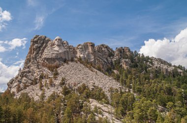 Black Hills, Keystone, SD, ABD - 31 Mayıs 2008: Mount Rushmore heykeli dağın eteklerinde mavi bulutların altında, yeşil orman gri granitin üzerinde.