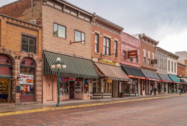 Deadwood SD, ABD - 31 Mayıs 2008: Downtown Main Street. Harley Davidson ve tuğla binalardaki diğer dükkanlar iş sırasını oluşturuyorlar. Yayalar işte. Ticari görüntüler renk ekler.