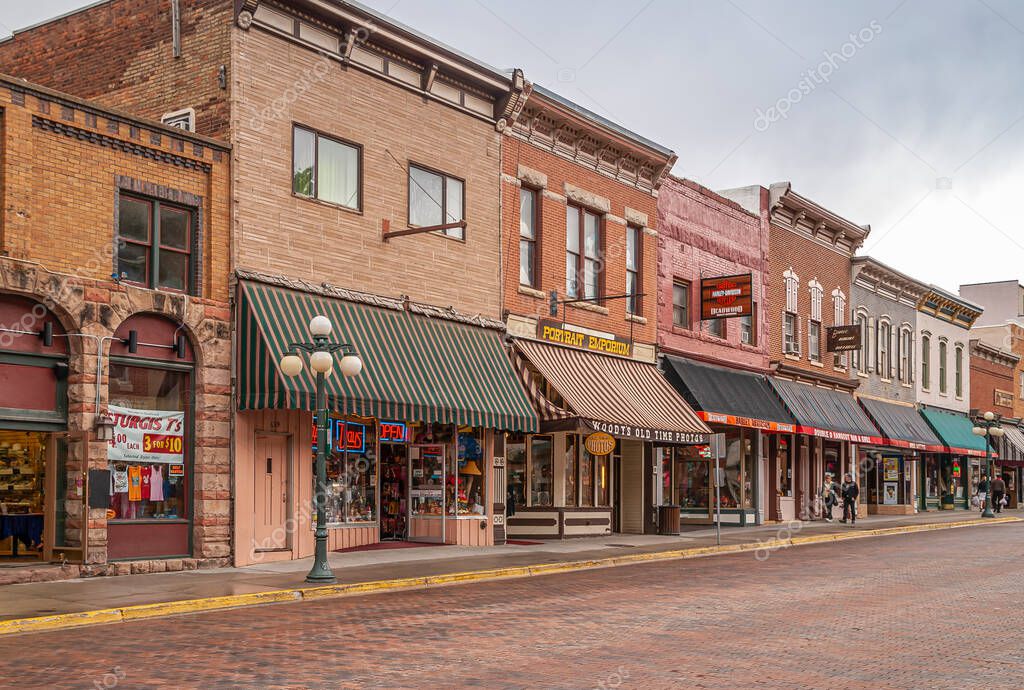 Deadwood SD, USA - May 31, 2008: Downtown Main Street. Harley davidson and other stores in brick buildings forming business row. Pedestrians. Commercial displays add colors.