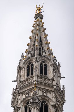 Brüksel, Belçika - 31 Temmuz 2021: Gri gökyüzüne karşı belediye binasının tepesindeki gri taş bina. Altın Aziz Michael ejderhayı öldürüyor..