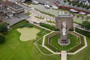 Diksmuide, Flanders, Belçika - 3 Ağustos 2021: PAX Kapısı 'nın havadan görünüşü ve IJzertoren' deki mezar harabesi. IJzer Nehri 'nde yeşil gölet ve eğlence teknesi.