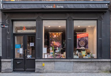 Brugge, Flanders, Belçika - 4 Ağustos 2021: Cook and Serve mağazası yemek ve içeceklerle konuklara servis yapmak için gereken her şeyi satar. Siyah duvarlar, geniş pencereler ve giriş kapısı..