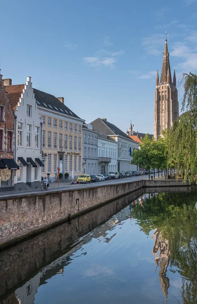 比利时佛兰德布鲁日 2021年8月4日 安静的潜水运河 反映圣母院塔和蓝天 上面有绿叶 街边有楼有车 — 图库照片