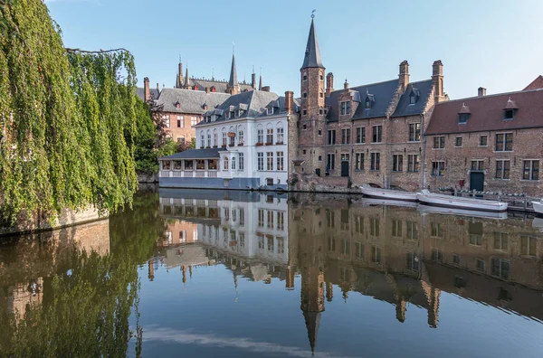 比利时佛兰德布鲁日2021年8月4日 安静的潜水运河在浅蓝色的天空下反射着褐色的石头 Huidevettershuis和白漆的Duc Bourgogne餐厅 旁边是绿色的叶子 — 图库照片