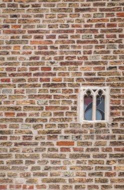 Brugge, Flanders, Belçika - 4 Ağustos 2021 Gruuthuse Sarayı 'nın kahverengi tuğlalı duvarında en küçük casus penceresi. 