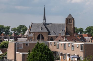 Sluis, Hollanda - 5 Ağustos 2021: Sint Johannes de Doperkerk (Vaftizci Yahya) mavi bulutların altındaki evlerin üzerinde yükseliyor.
