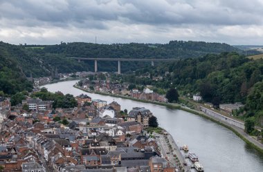 Dinant, Wallonia, Belçika - 8 Ağustos 2021 Kale. Meuse Nehri 'nin yukarısındaki Charlemagne köprüsü yoğun bulutların altında. Yeşil ormanlık tepeli şehir manzarası.
