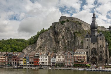 Dinant, Wallonia, Belçika - 8 Ağustos 2021 Kale. Brown Stone Koleji Notre Dame de Bellevue inşaat kompleksi. Sağanak yağmurlu bulutların altında, yeşil ormanlık tepenin önünde..