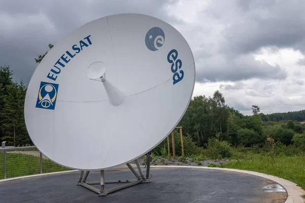 Transinne, Wallonia, Belçika - 10 Ağustos 2021: Euro Space Center. Yağmurlu bulutlar altında yeşil alan adı üzerinde Eutelsat anteninin modeli.