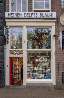Amsterdam, Hollanda - 13 Ağustos 2021: Prinsengracht 440 'taki Heinen Delfts Blauw hediye dükkanının önü. Ekranda tipik mavi seramik hediyeler ve çatal bıçaklar bulunan küçük pencere