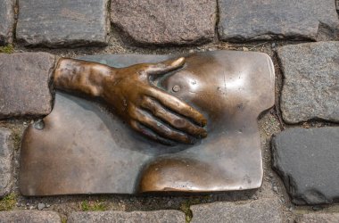 Amsterdam, Hollanda - 14 Ağustos 2021: Oude Kerk (eski kilise) yakınlarındaki kaldırım taşları arasında yer alan kadın göğüs heykeli üzerine el)