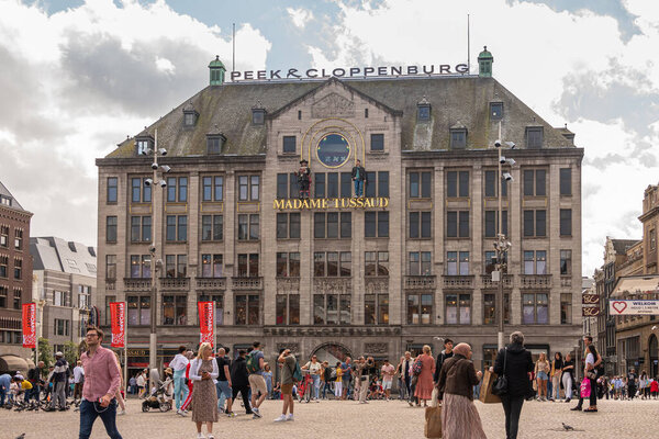 Amsterdam, Netherlands - August 14, 2021: Brown stone Peek and Cloppenburg building on Dam square housing Madame Tussaud wax museum. Clothing of lots of people add colors.